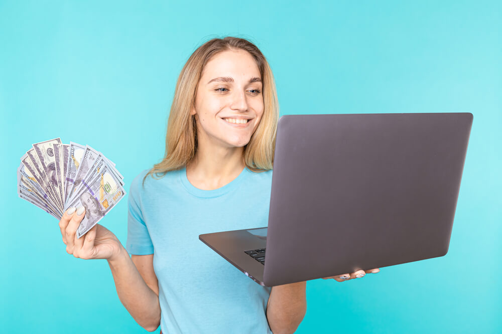 happy woman with title pawn cash in one hand and laptop in other hand for title pawn research