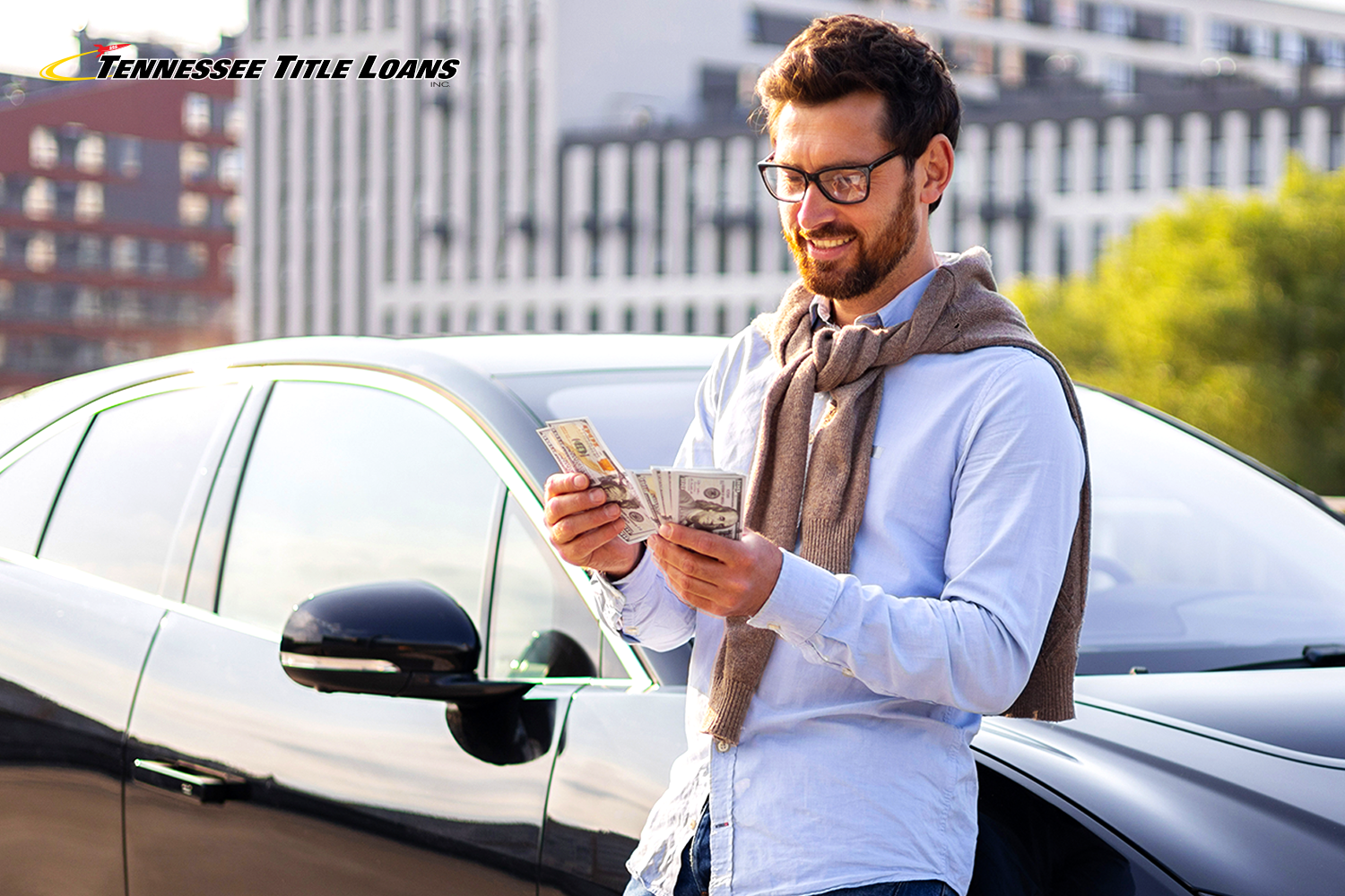 man holds title loan cash outside of his car