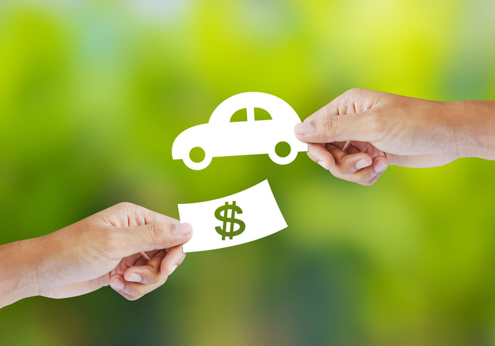 one hand holding paper car and one hand holding cash symbol for cash for title loans