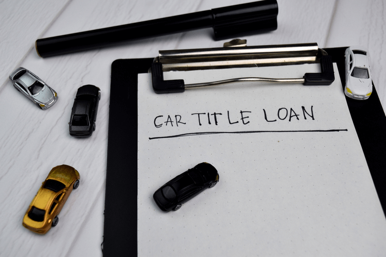 clipboard that reads online car title loan with toy cars on desk