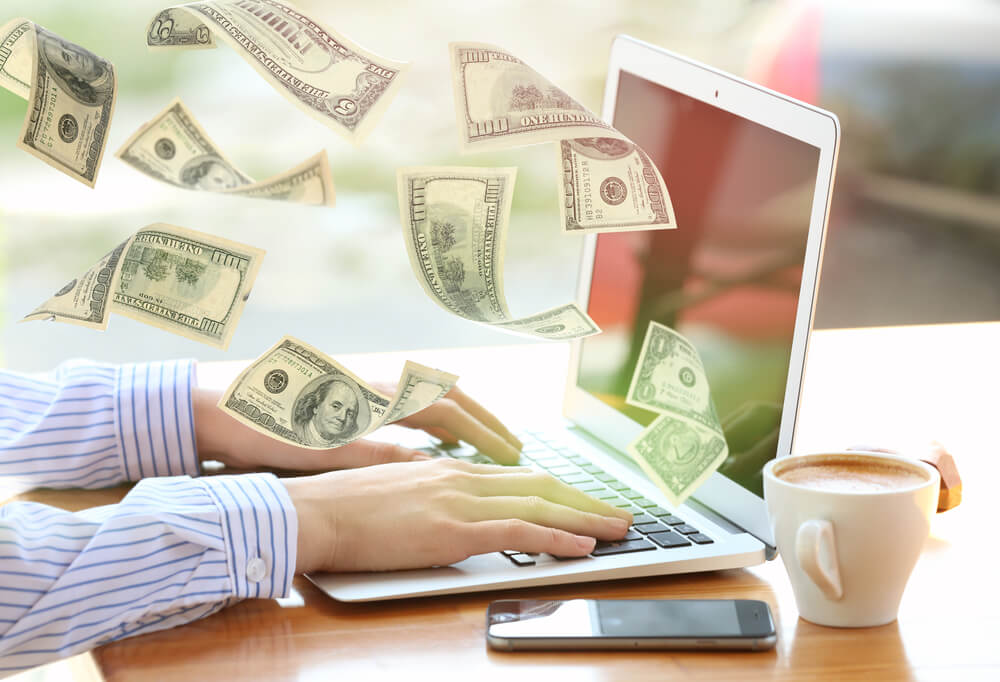 woman at laptop applying for title loan online with cash flying from the screen