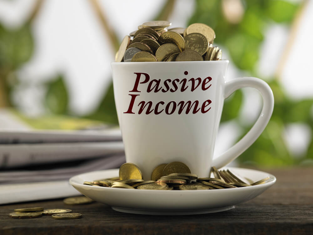 coffee mug filled with coins and has written of passive income on it