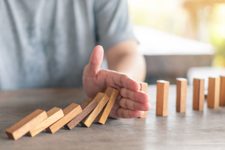 man using his hand to stop wood block from falling for symbolizing the use of a Title loan