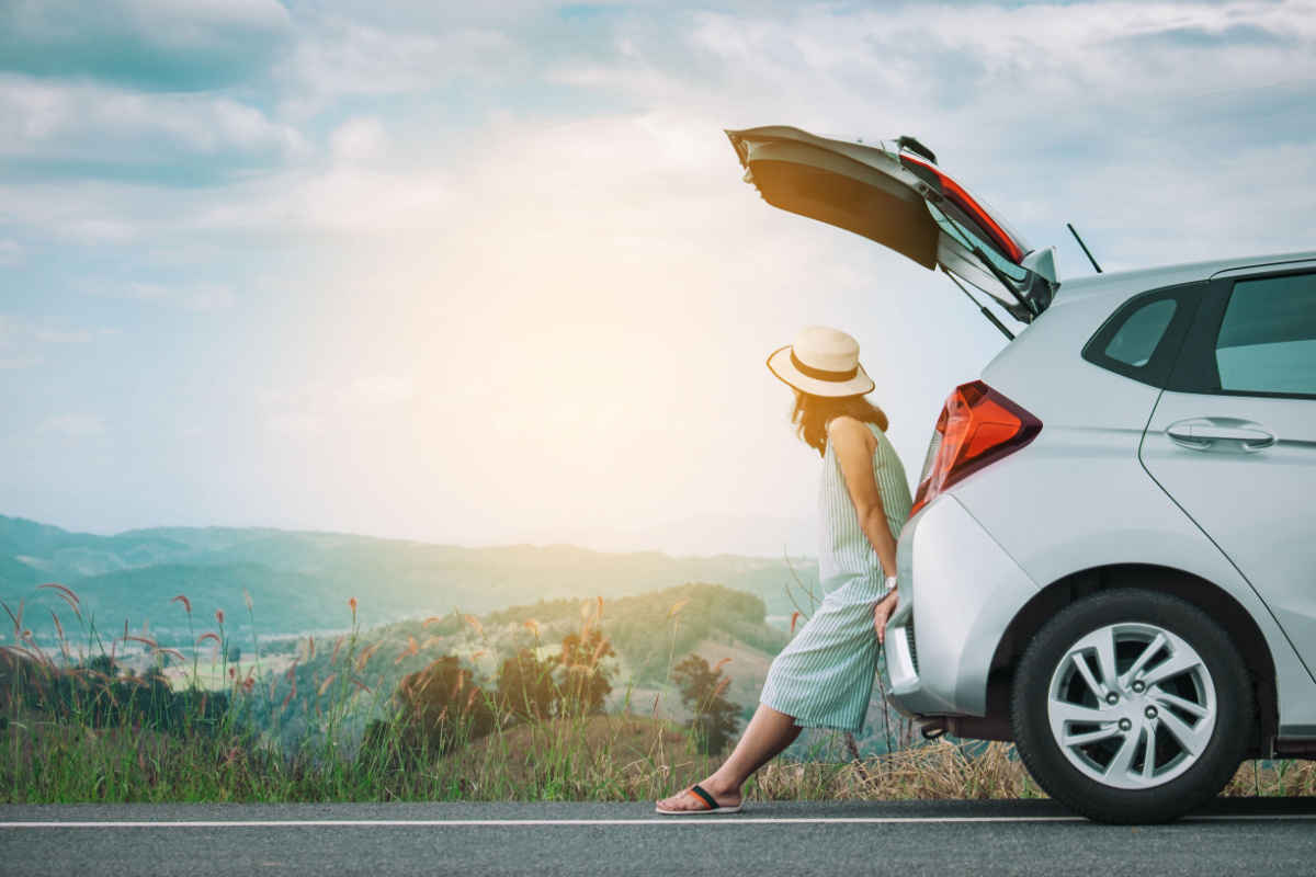 woman sitting on trunk of car needing emergency funds from a title loan