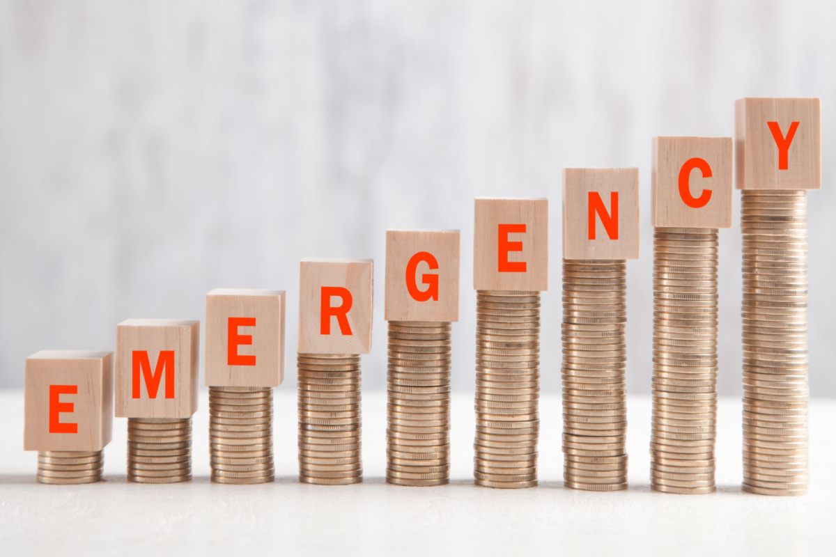 Emergency Written on Blocks with a Bundle of Coins Representing an Upward Trending Graph