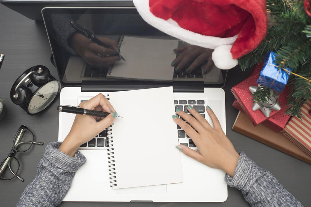 person writing down holiday planning budget with their notepad