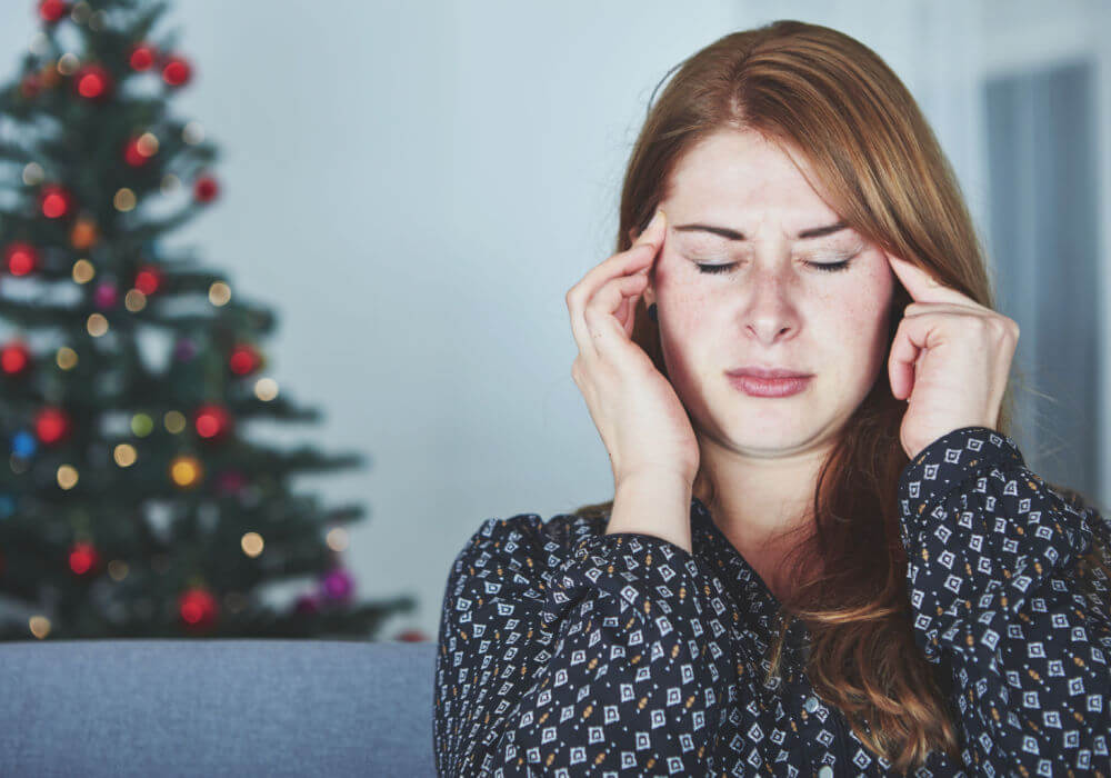 A white woman holds her fingers to her forehead because of a Christmas financial crisis.