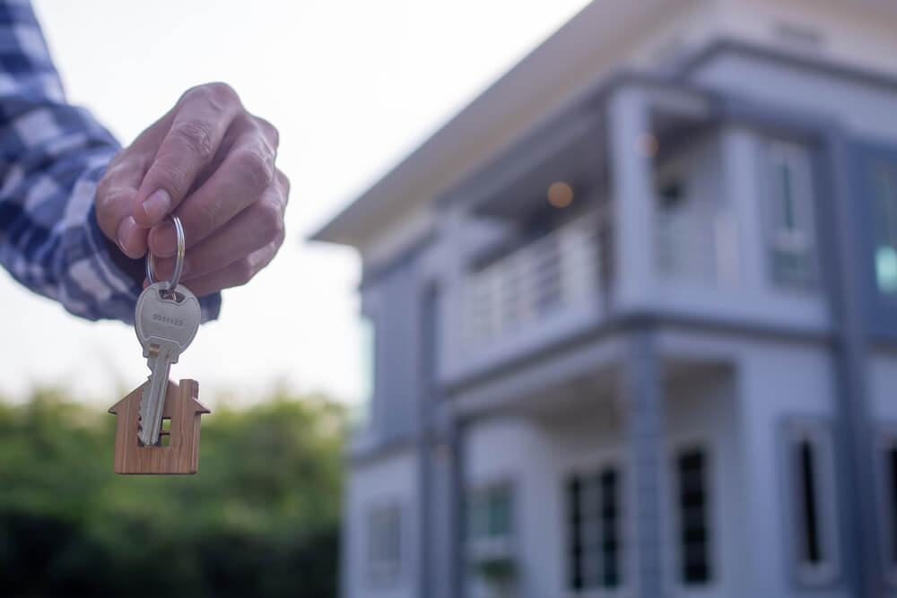 person holding key to real estate investment home