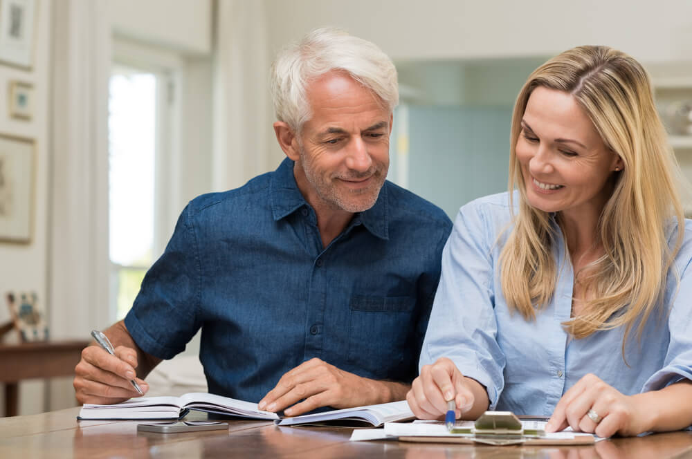 A white couple reviews their finances and smile.