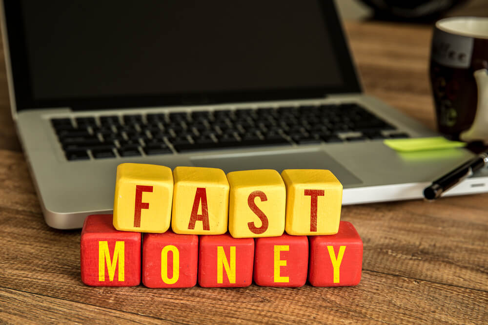 fast money spelled with blocks with laptop