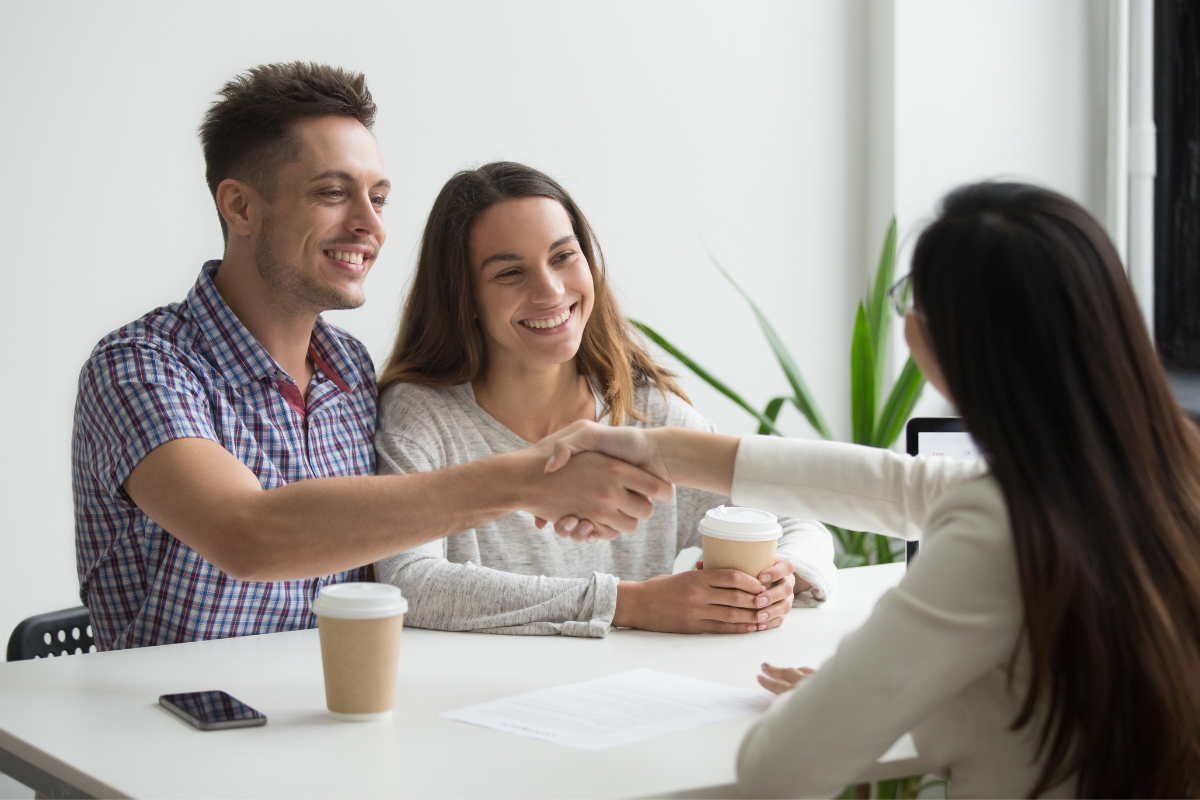 happy couple shaking loan agents hand