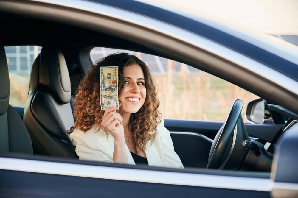 woman holding her title loan money in the car