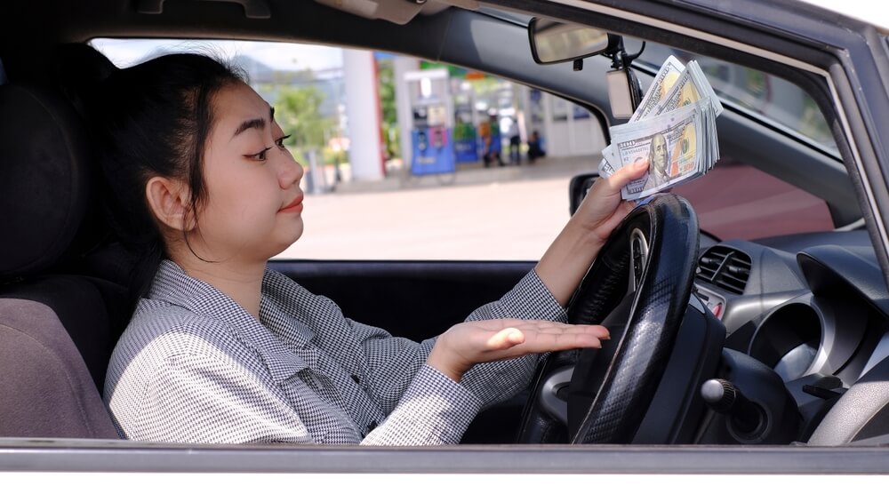 girl in car showing her title loan money