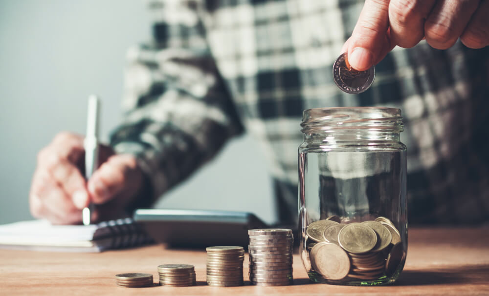 man saving money in jar with writting his budget