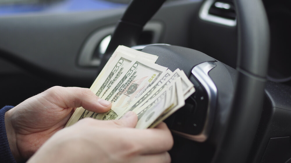 man counting title loan cash in his car