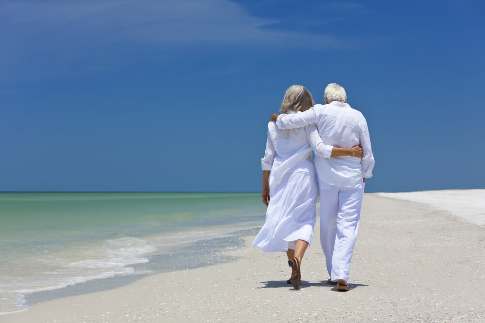 retired couple walking on beach