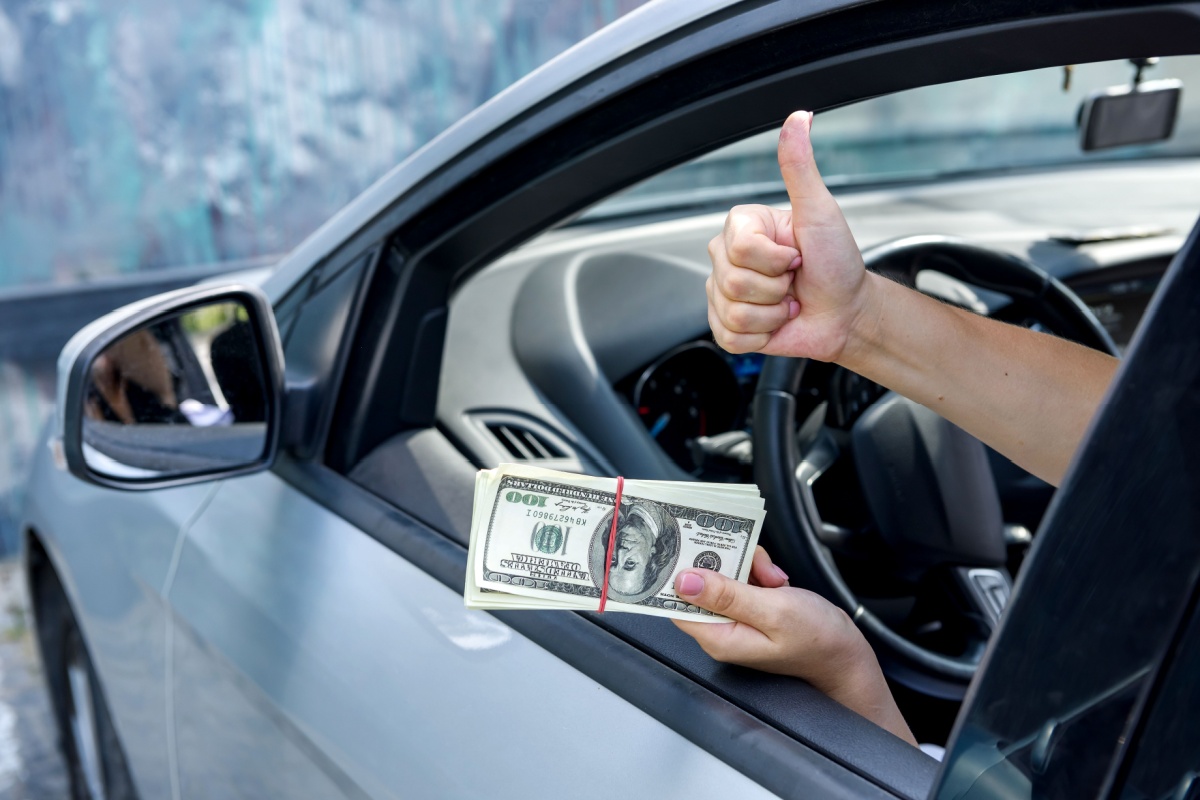 person holding title loan cash outside of car
