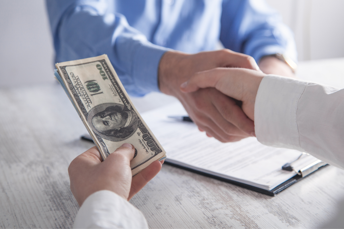 representative handing borrower cash and shaking hands over loan approval
