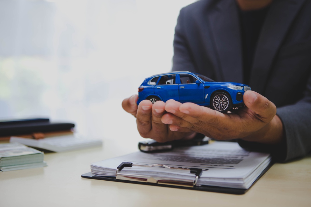 man holds toy truck while explaining the title loan process with application on desk