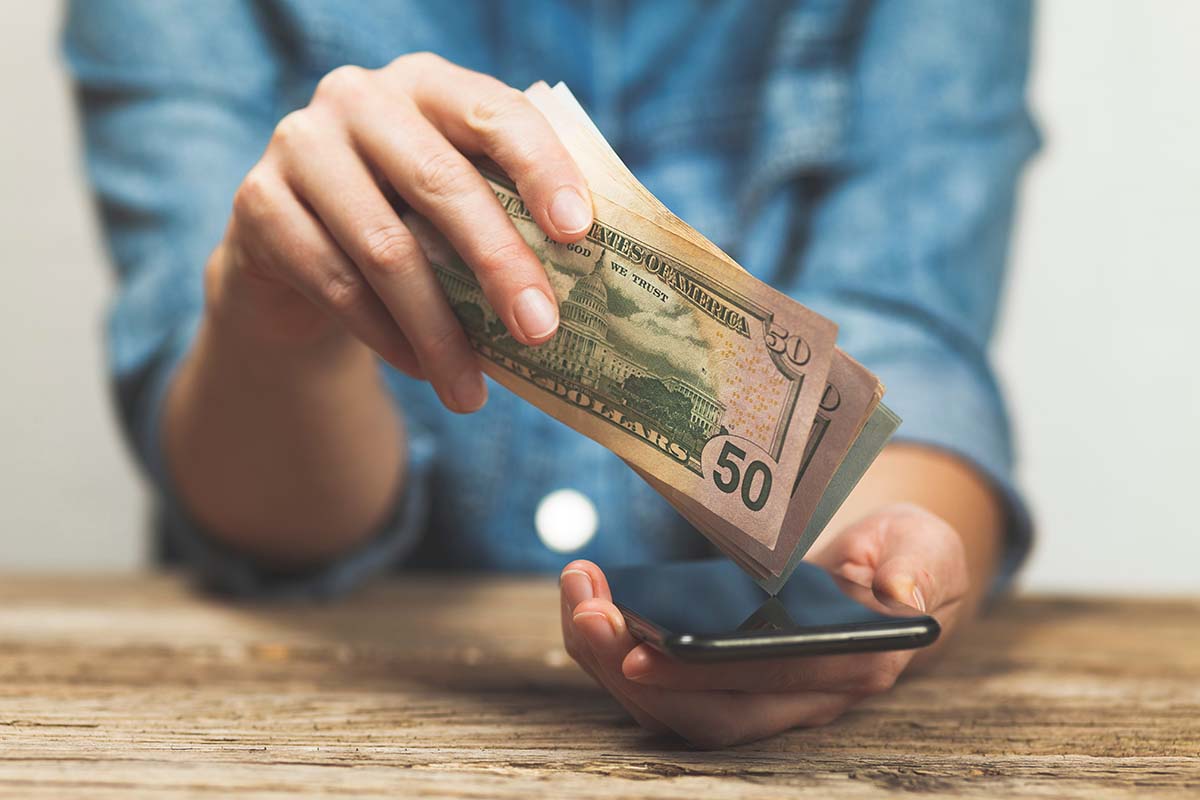 person using the phone and holding title loan cash in hand