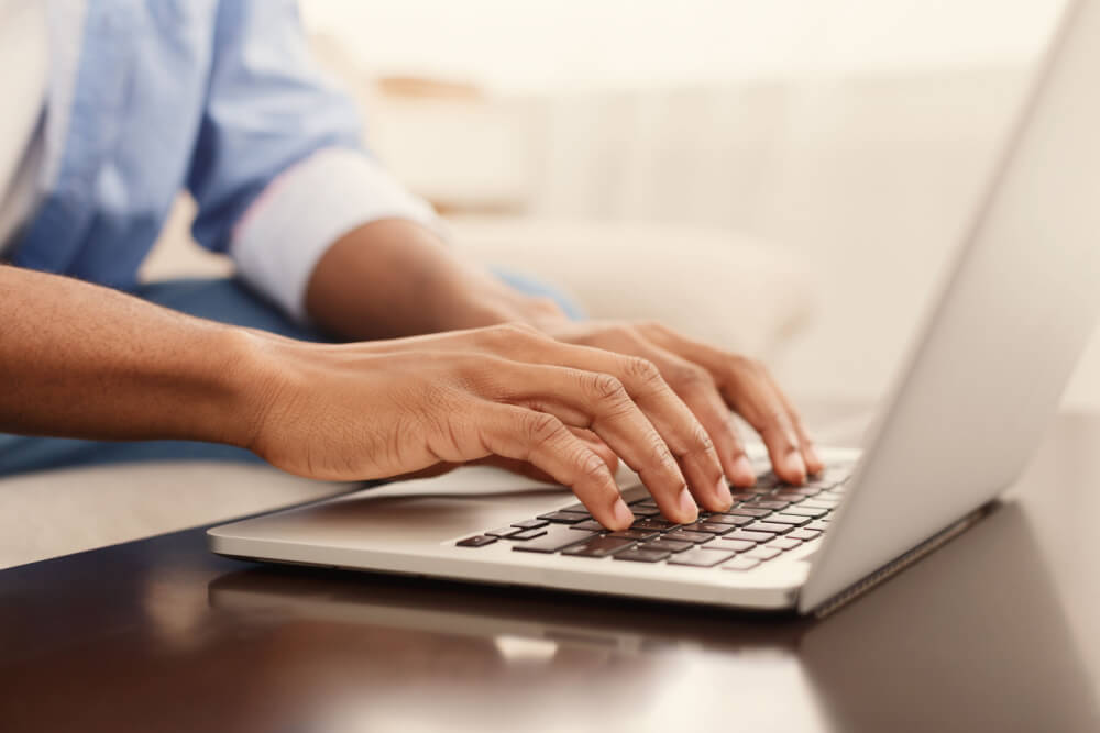 Online payday loans: a man sitting with a white laptop on a brown table.