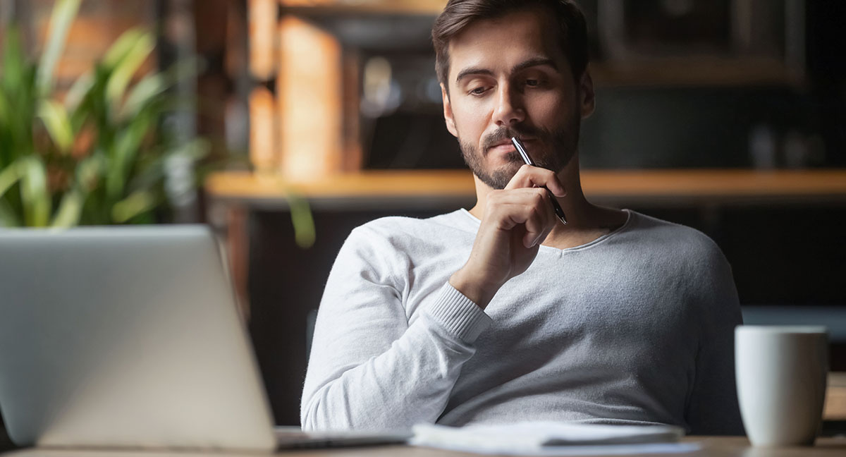 man thinking in his office about paying off debt, saving money, and getting a registration loan