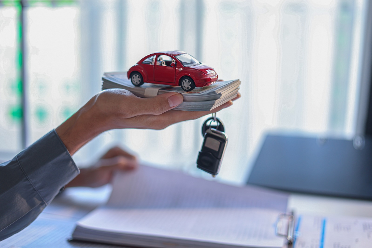 person holding a toy car keys and money in hand