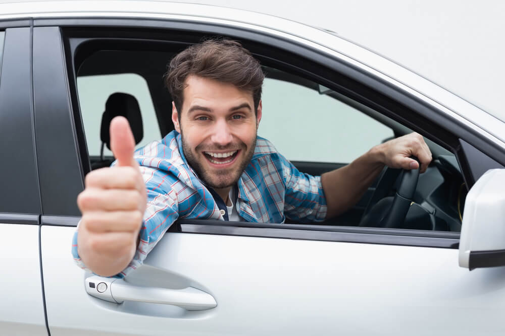 Man in car gives thumbs up, expressing satisfaction with title loans.