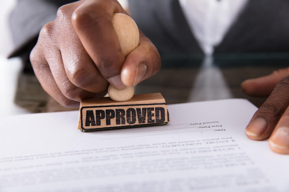 Qualifying for title loans with approved documents on top of a wooden table, and a man approves it.