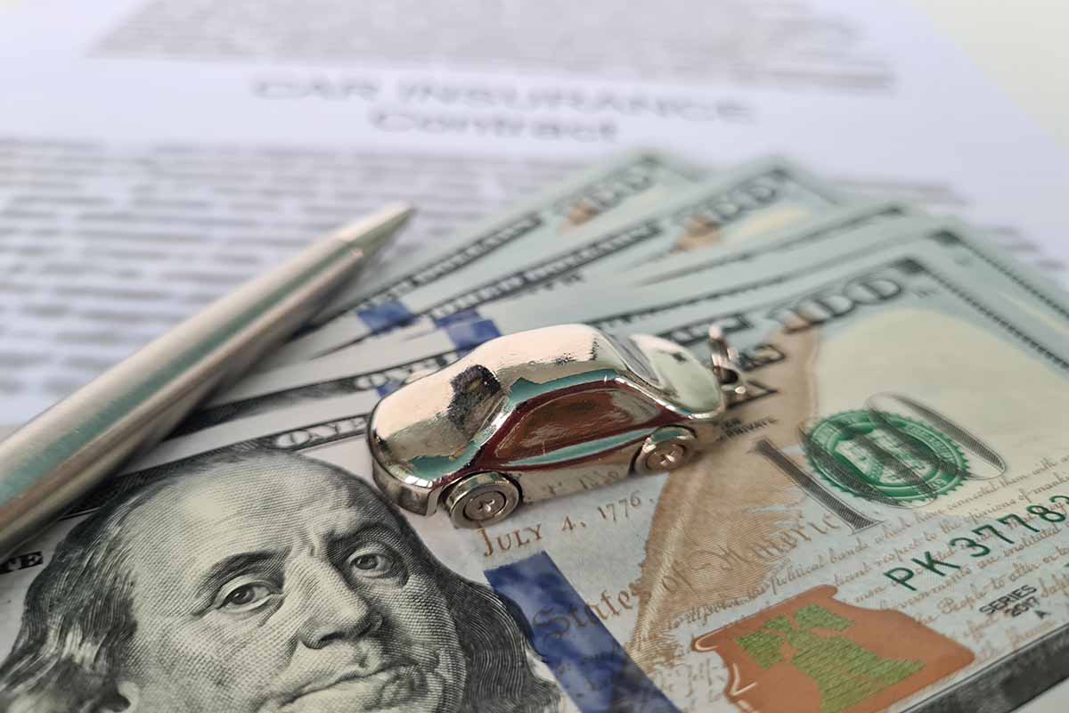 A close-up photo of a pile of hundred dollar bills and car keys, with papers related to loan registration in the background.