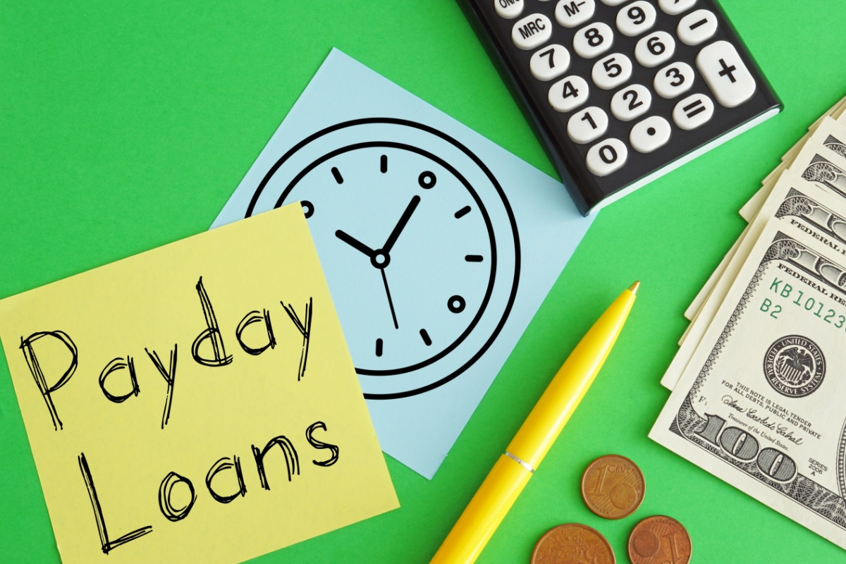 sticky note that says payday loans next to cash
