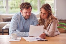 couple looking at cash loans for the unemployed in their kitchen and looking at installment loan paperwork