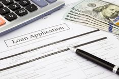 installment loan application, cash, and calculator on top of desk