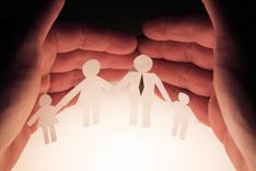 a pair of hands holding paper cut out of family for safety and getting an emergency auto title loans