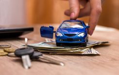 car registration loan cash on top of desk with blue toy car