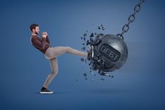 man kicking wrecking ball to get out of debt faster