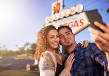 Couple taking photo in front of Las Vegas sign and is needing to get installment loans money for help