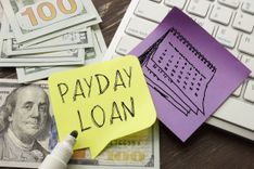 payday loan written on note on top of desk with cash and keyboard