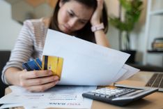 frustrated woman with bad credit looking at overdue bills and needing a car title loan to pay debt off