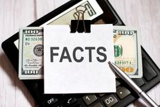 car title loan cash clipped together with note that reads FACTS on top of calculator on desk