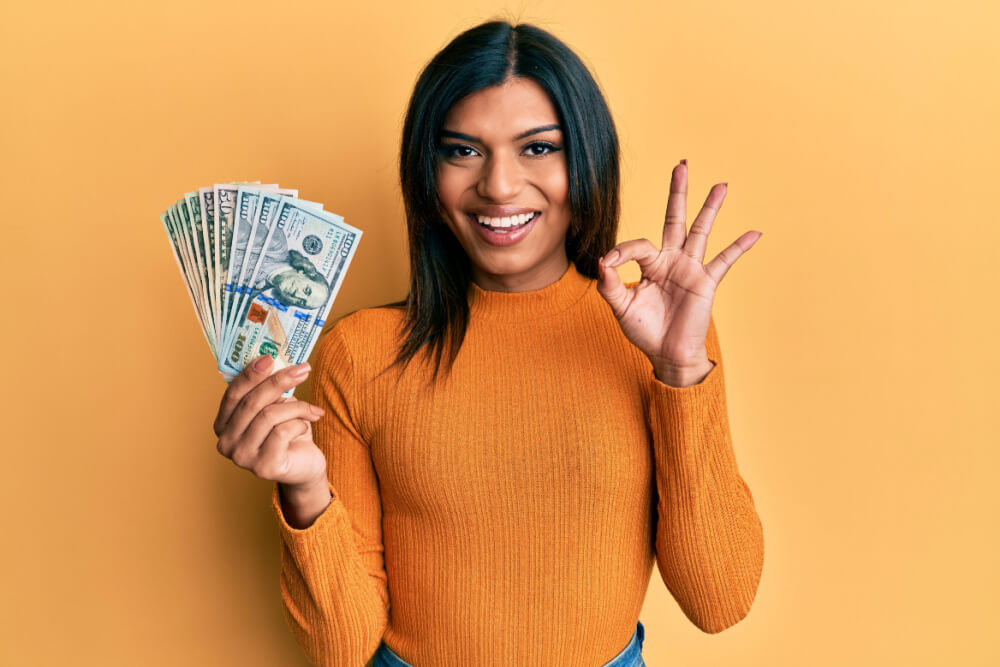 woman making the okay the gesture with one hand and title loan money in the other