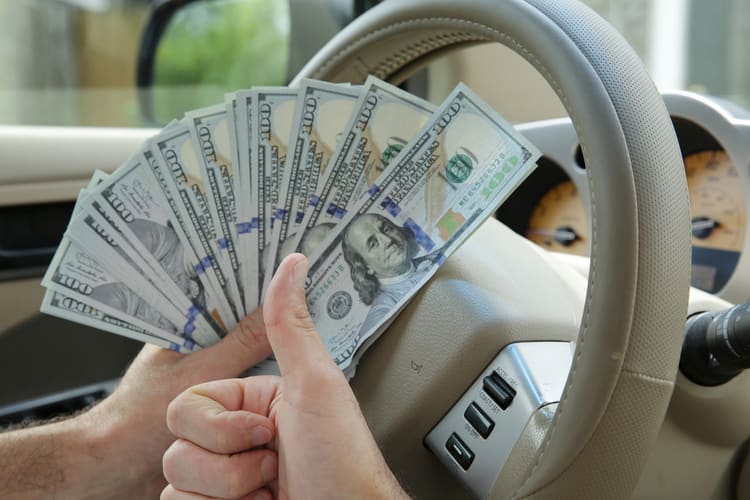 man holding title loan cash in car