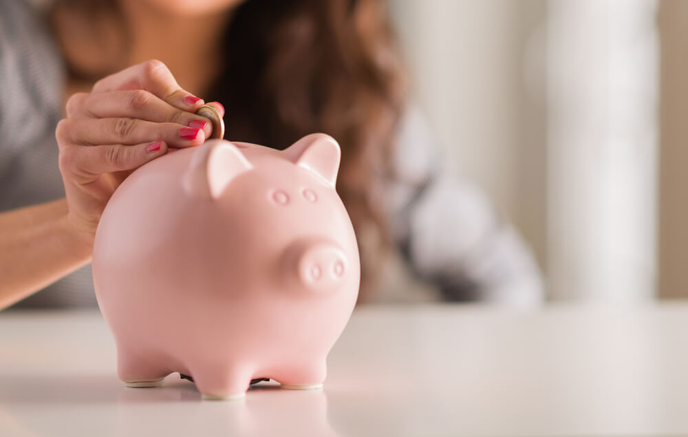 person putting coins in piggy bank for saving money household