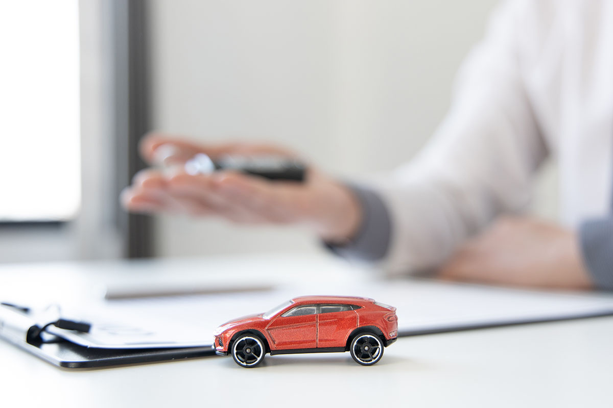 Representative reviewing car title loan and toy car on desk