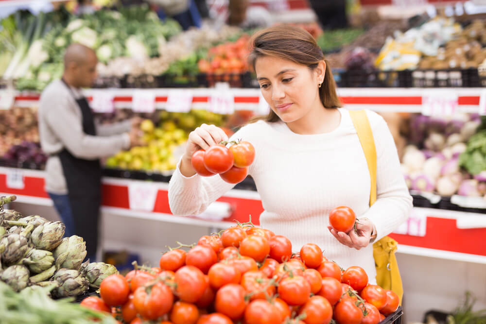 woman grocery shopping looking at tomatoes